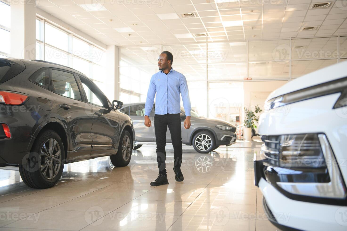 hermoso africano hombre elegir un nuevo coche a el concesión foto