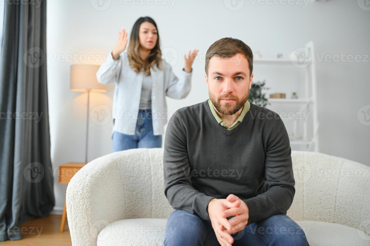 Family quarrel, man and woman sitting on sofa at home. angry woman yells at her husband photo