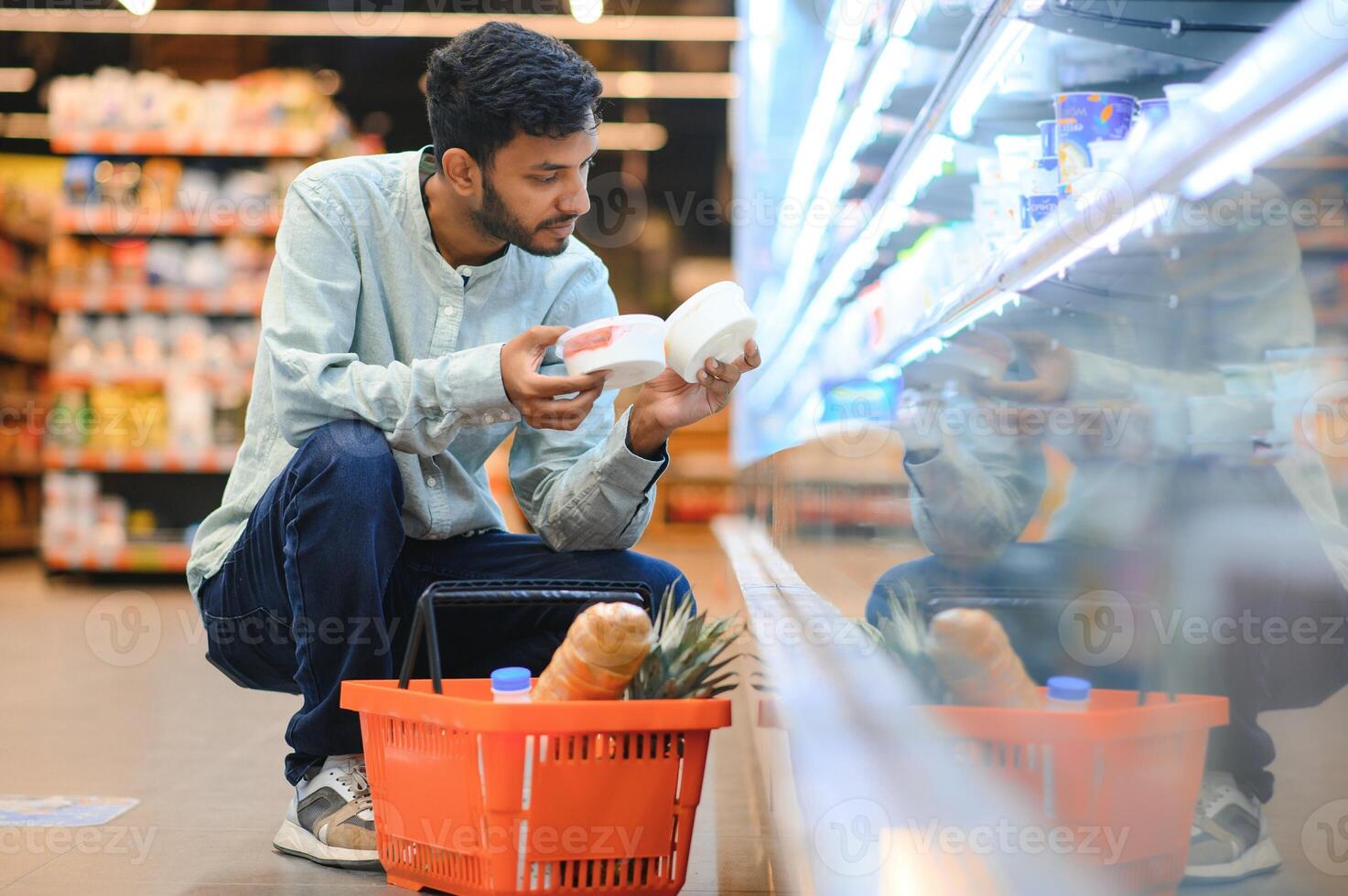 Portrait of handsome young Indian man standing at grocery shop or supermarket, Closeup. Selective Focus. photo