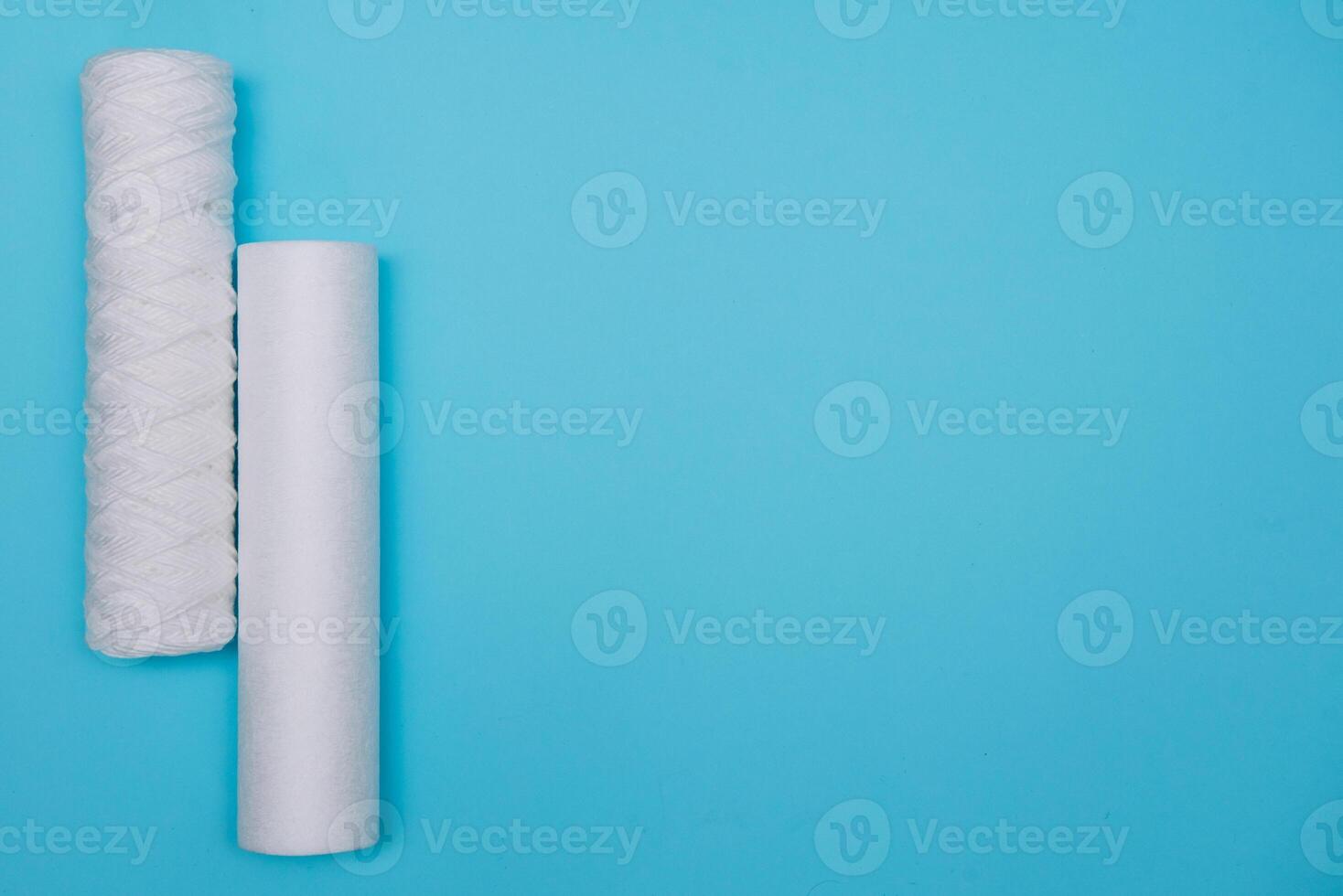 Water filters. Carbon cartridges and a glass with water on a blue background. Household filtration system. photo