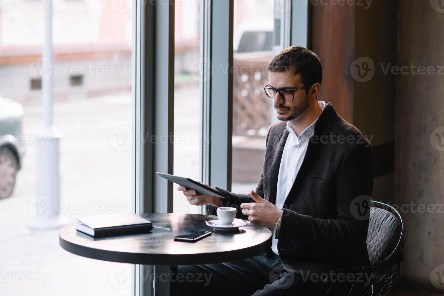 a man sitting in a cafe with tablet. Casual Man Using Tablet Computer Sitting in Cafe Surfing Internet photo