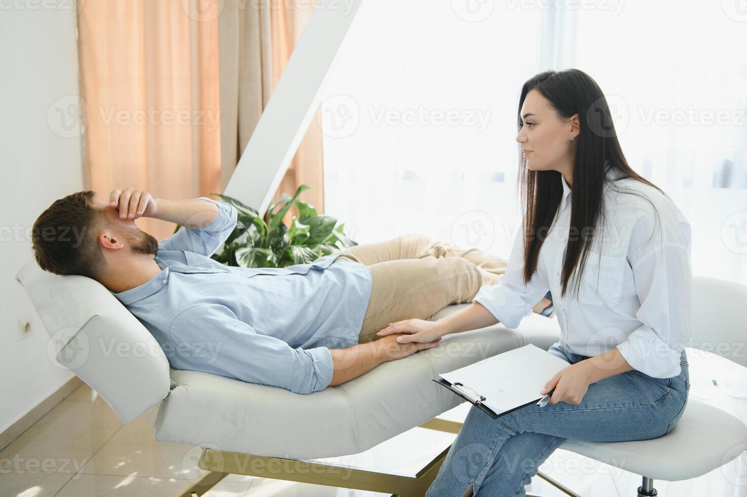 Depressed man speaking to a therapist while she is taking notes photo