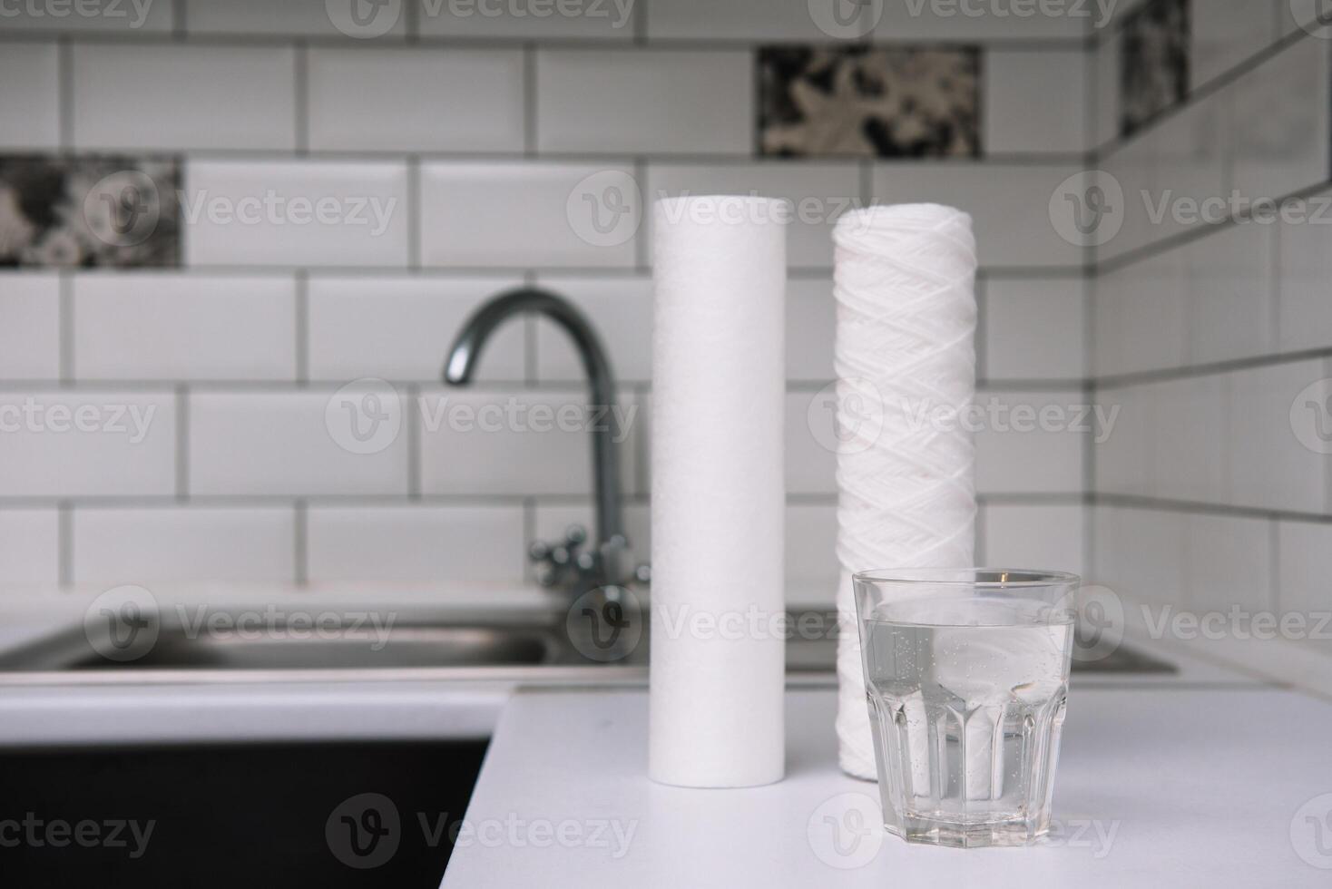 Water filters. Carbon cartridges and a glass on a white kitchen background. Household filtration system photo