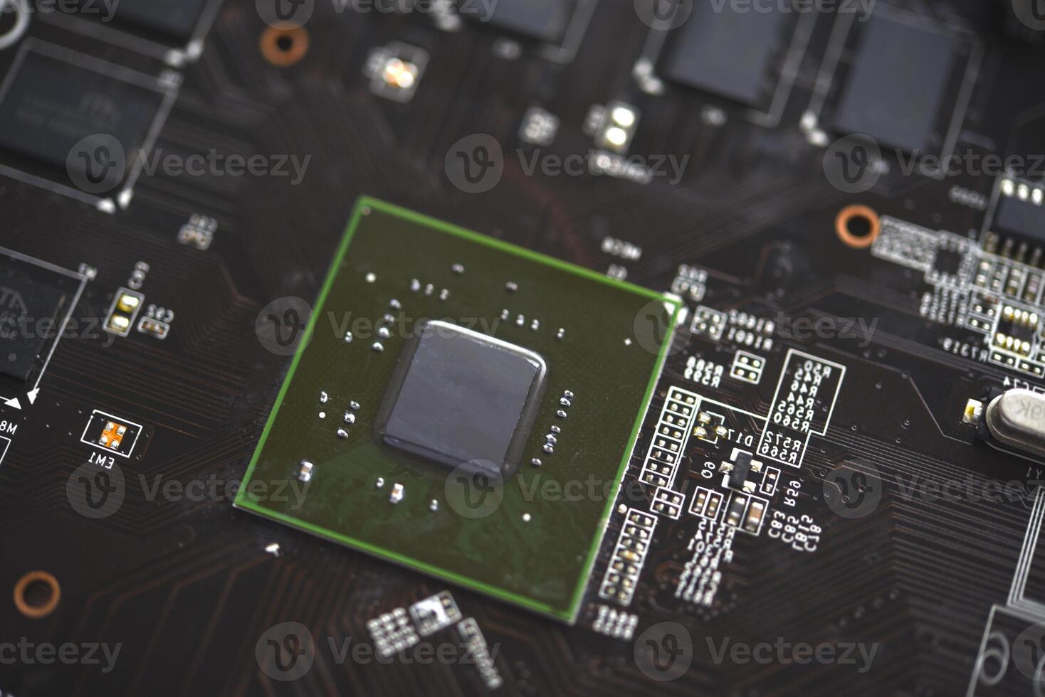 A brown printed circuit board with a processor chip and memory strips. Electronic components on the graphics card. photo