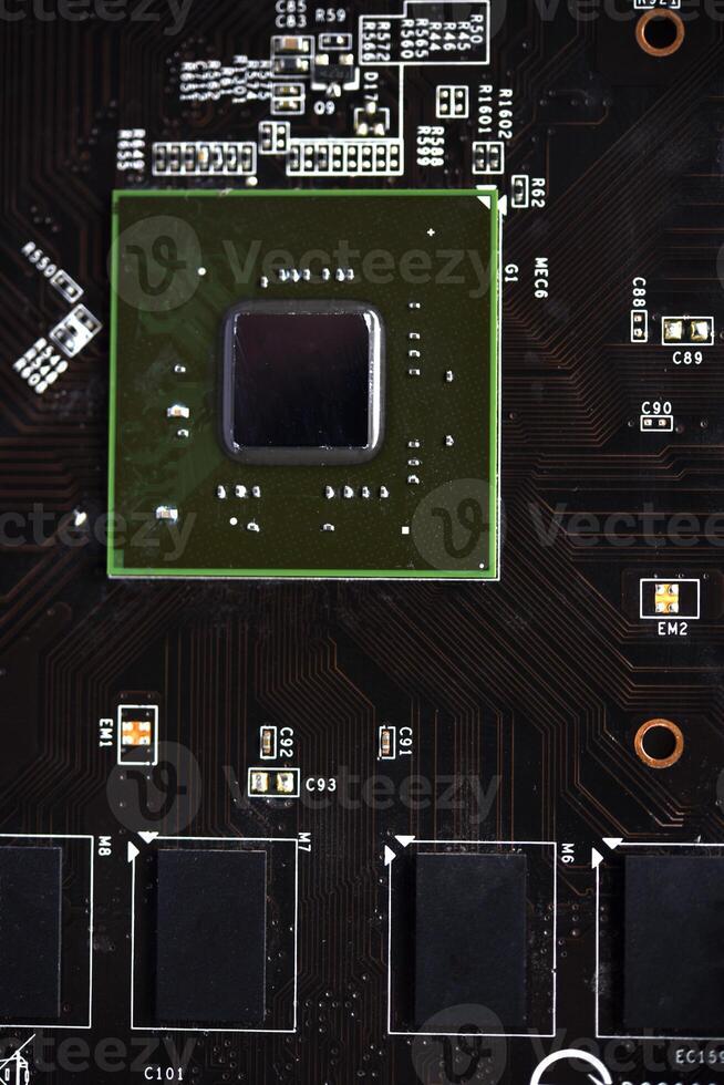 A brown printed circuit board with a processor chip and memory strips. Electronic components on the graphics card. photo