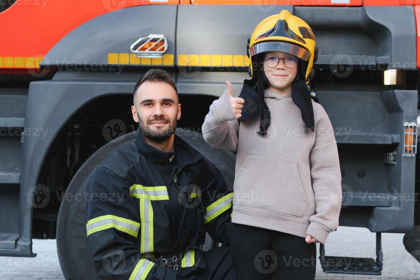 A fireman shows his work to his young son. A boy in a firefighter's helmet photo