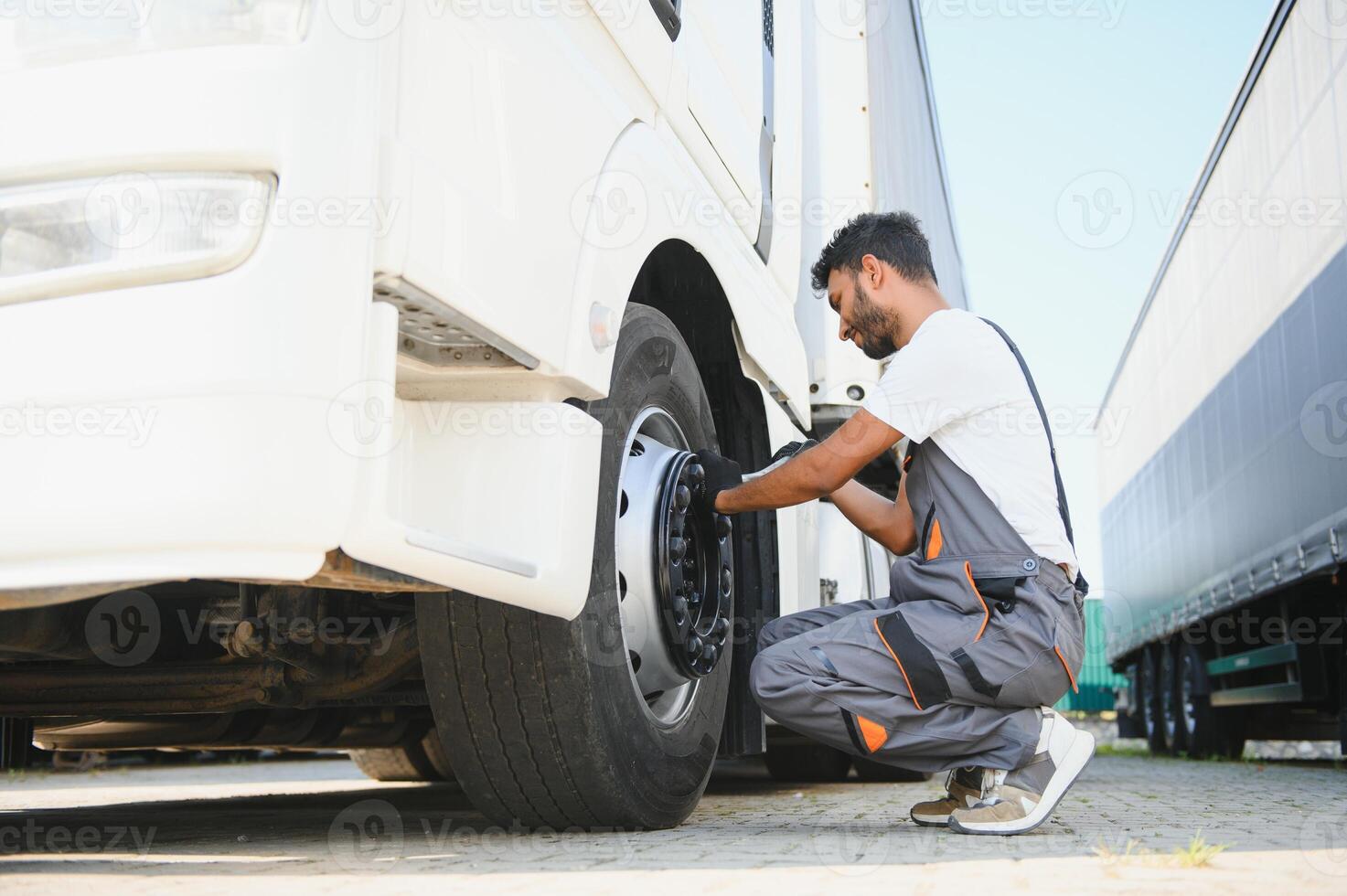 Indian Mechanic unscrews wheel truck pneumatic wrench photo