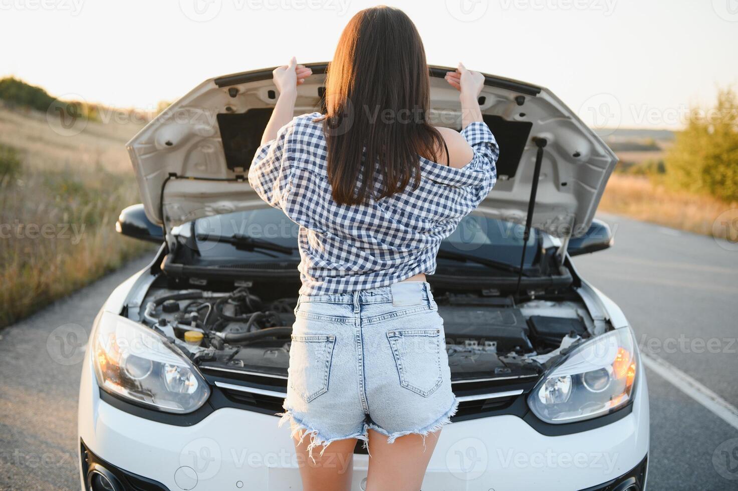 sexy girl stand by the broken car and don't know what to do. Rear view. photo
