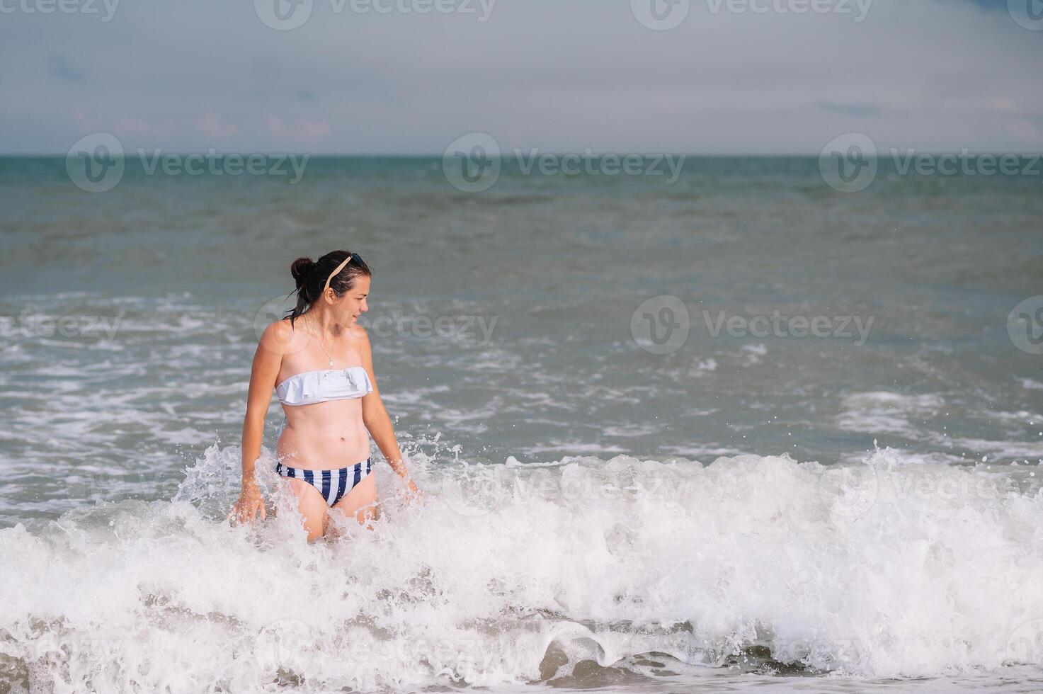 beautiful girl with pretty legs walking along the seashore in the summer hot day near the sea. photo