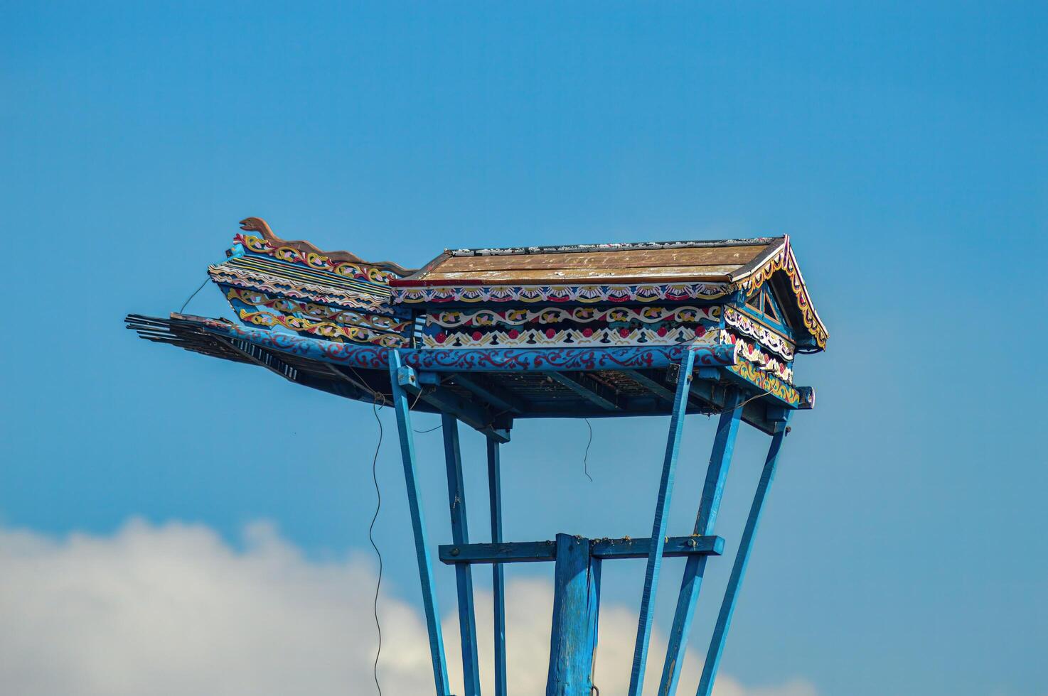 a traditional wooden dove house on a pillar against a cloudy blue sky background photo