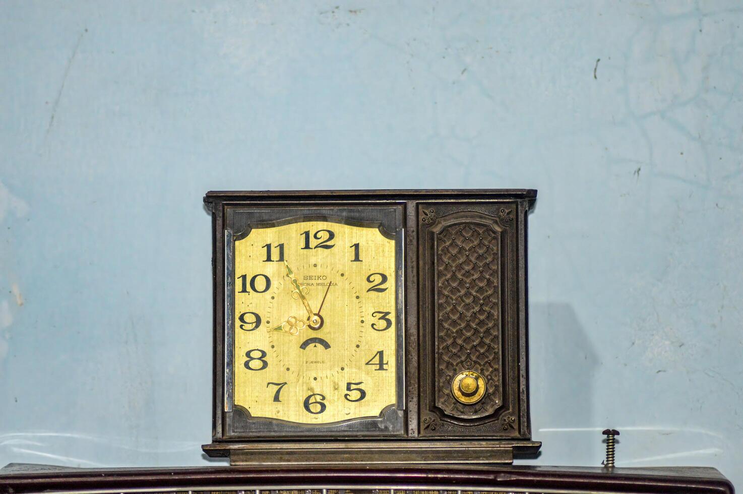 an old antique wooden clock against a plain wall background photo