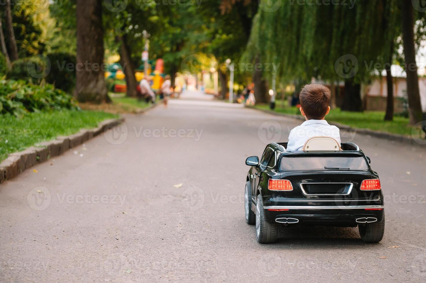 Cute boy in riding a black electric car in the park. Funny boy rides on a toy electric car. Copy space. photo