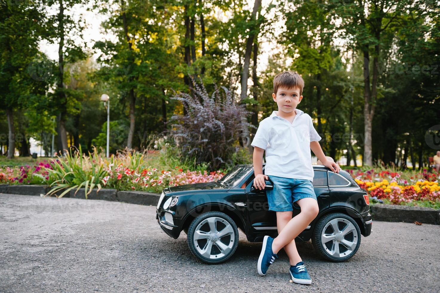 Cute boy in riding a black electric car in the park. Funny boy rides on a toy electric car. Copy space. photo