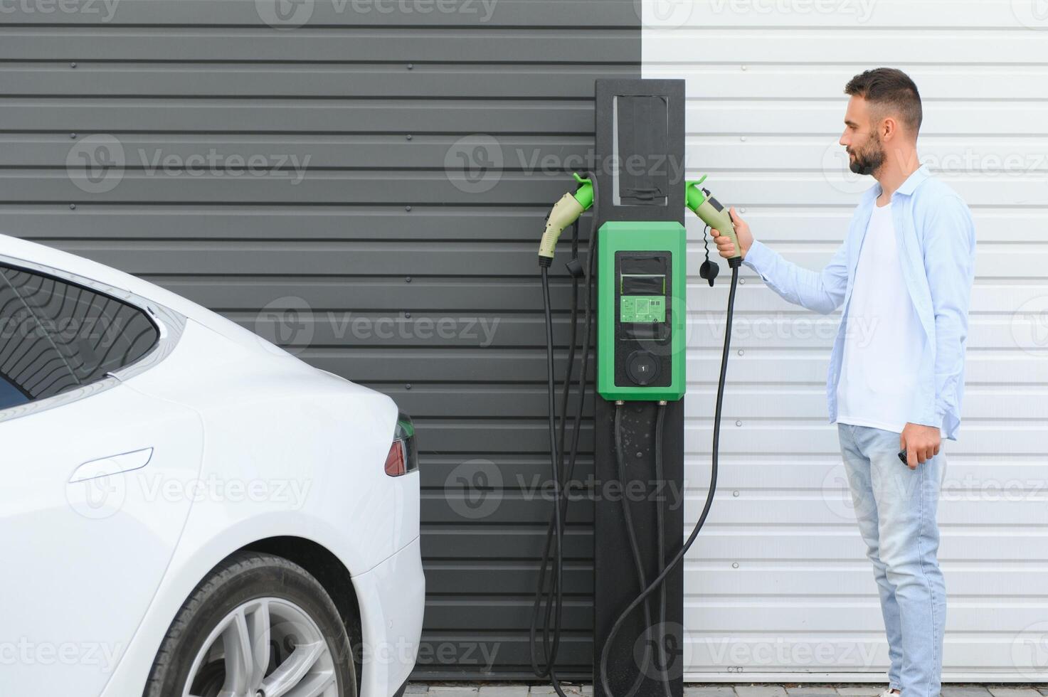 a man charges an electric car photo