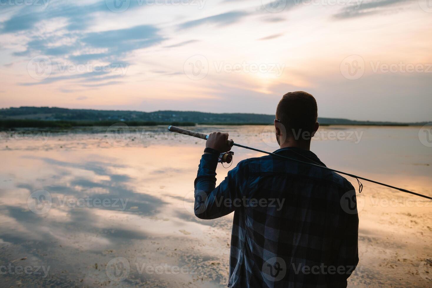 Fishing. spinning at sunset. Silhouette of a fisherman. photo