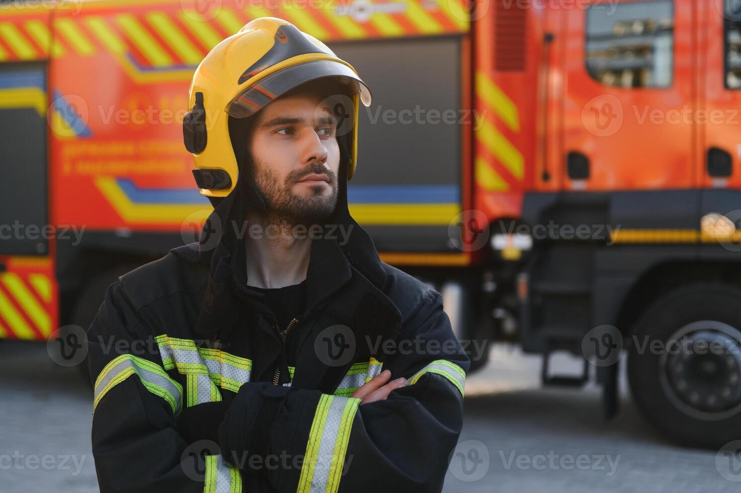 Firefighters man in a protective suit near fire truck. Protection, rescue from danger. Fire station photo