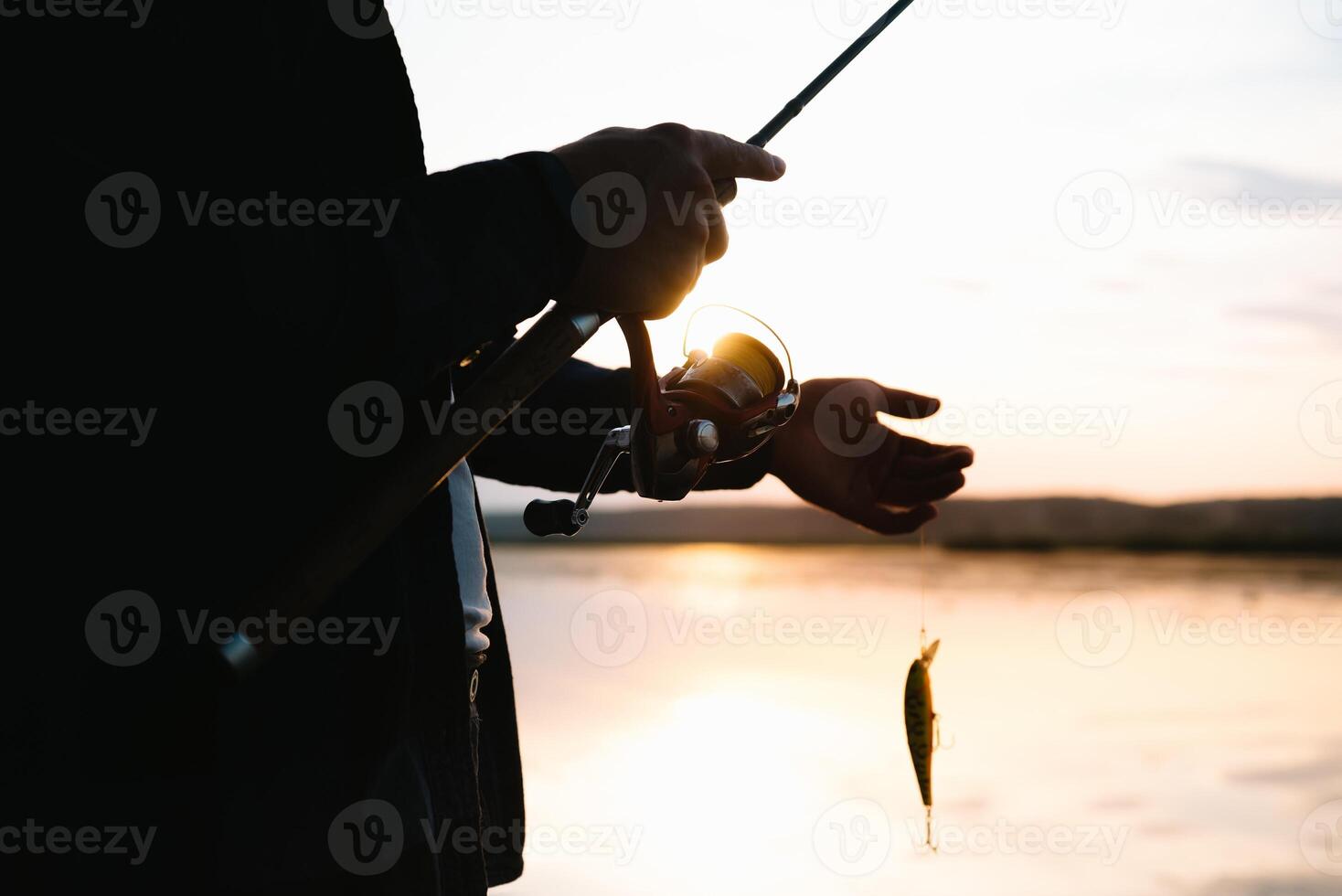 The fisherman's hands, holds the spinning rod, rotates the coil handle. Hobby and activity. photo