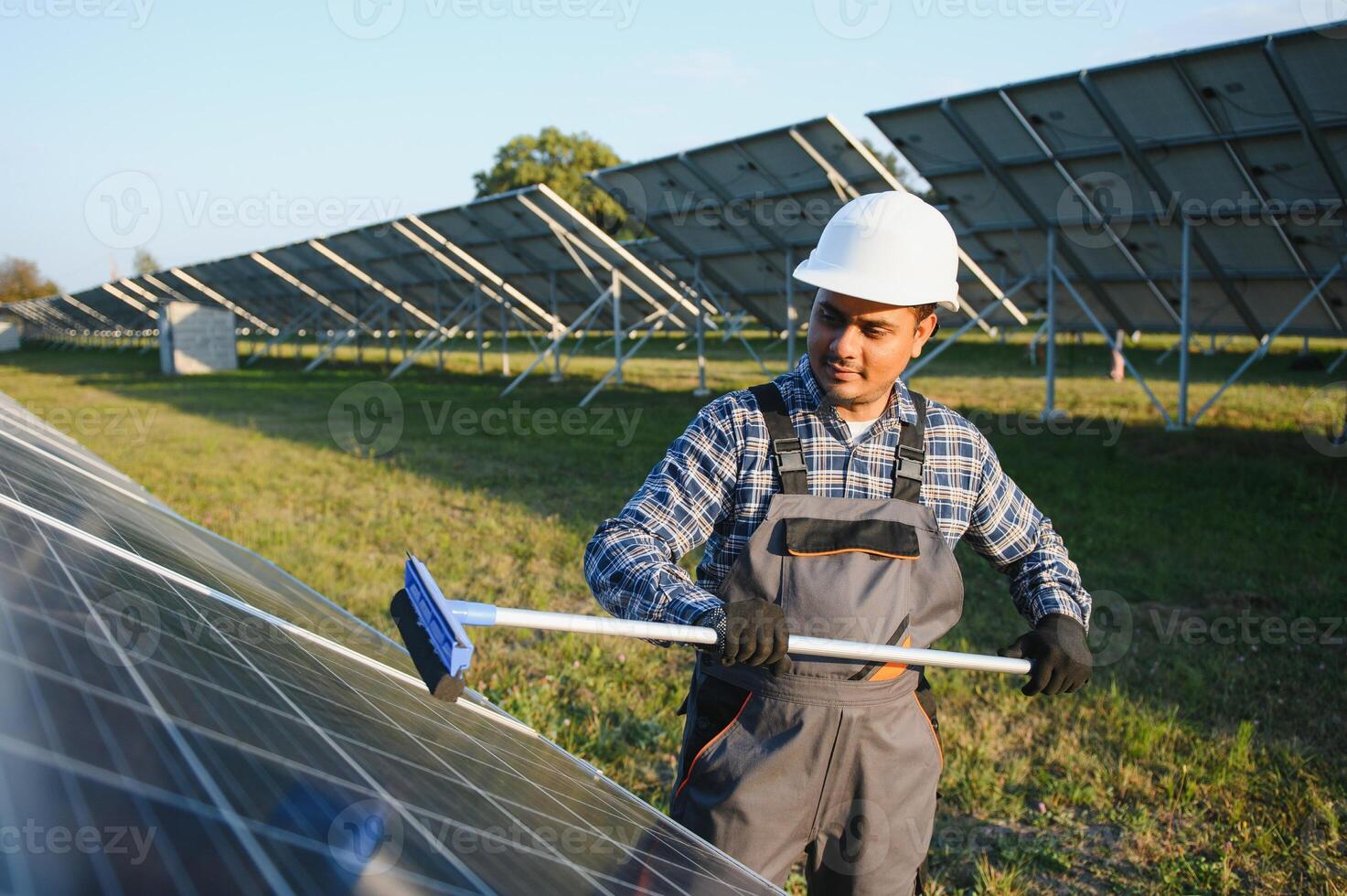 Indian handyman cleaning solar panels form dust and dirt photo