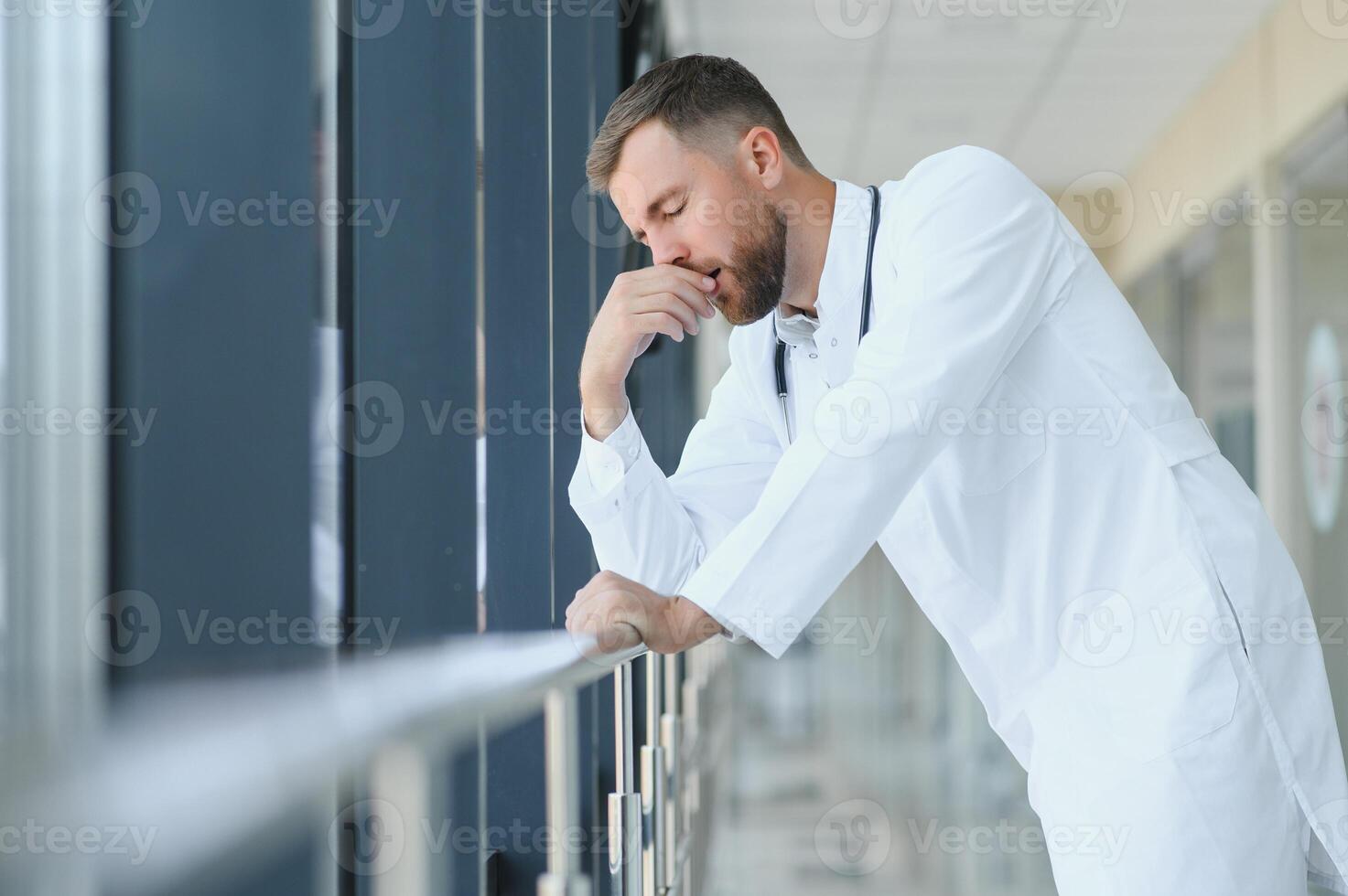 Sad doctor standing in hospital corridor photo