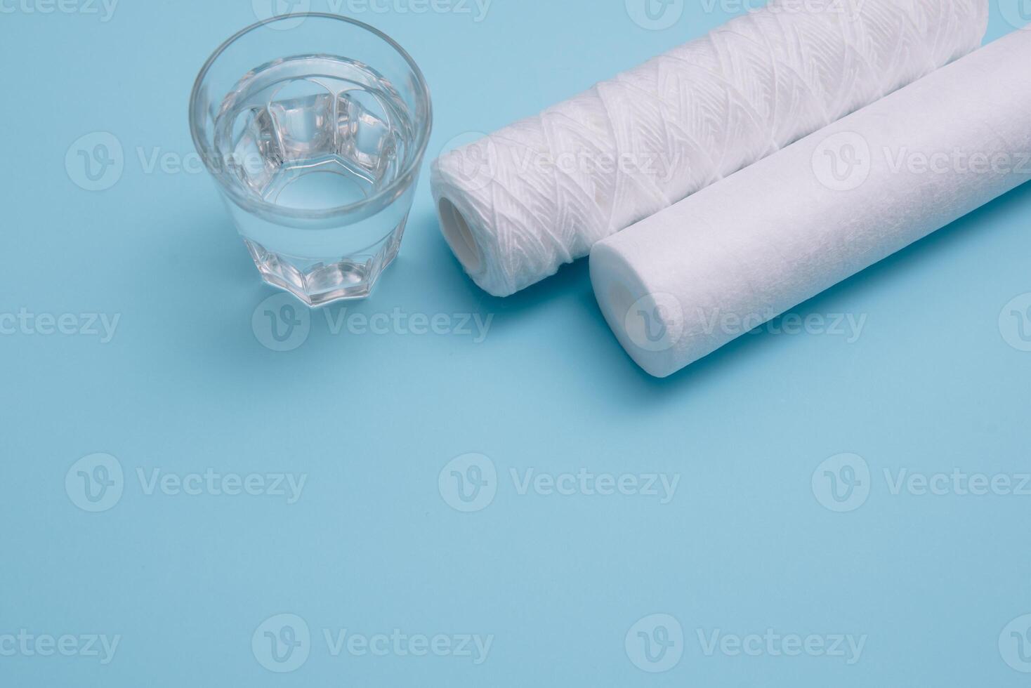 Water filters. Carbon cartridges and a glass on a blue background. Household filtration system photo