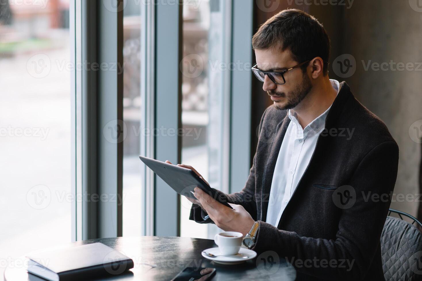 a man sitting in a cafe with tablet. Casual Man Using Tablet Computer Sitting in Cafe Surfing Internet photo