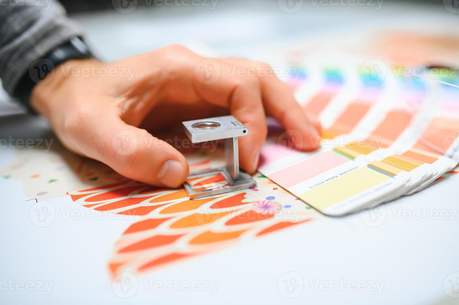 Print house worker controlling printing process quality and checking colors with magnifying glass photo