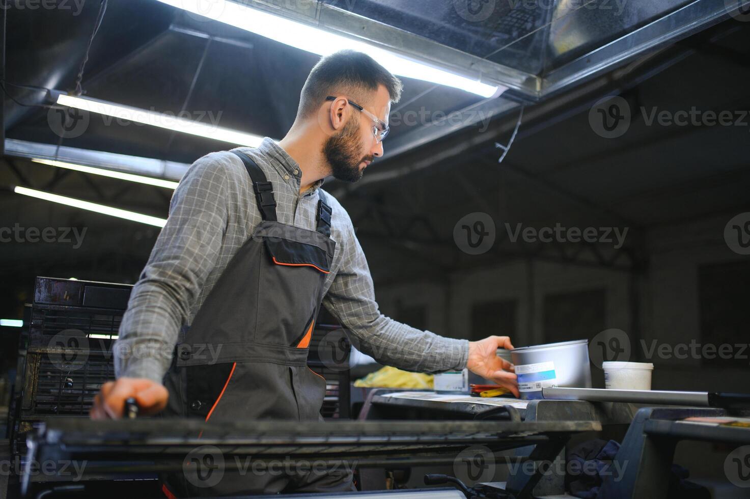 Man working in printing house with paper and paints photo