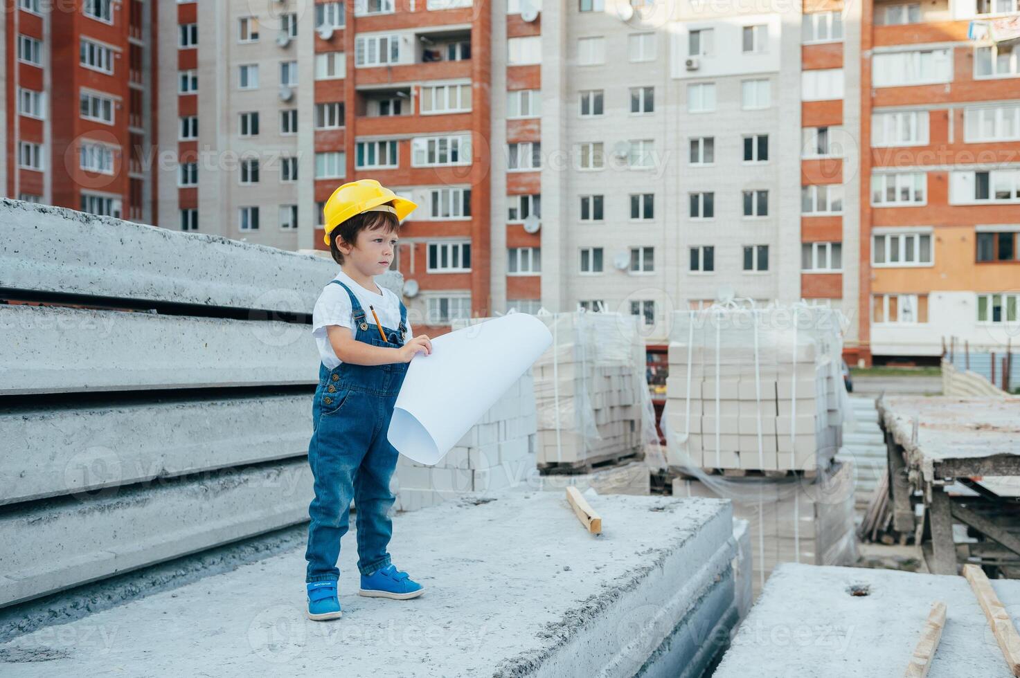 arquitecto en casco escritura alguna cosa cerca nuevo edificio. pequeño linda chico en el edificio como un arquitecto foto