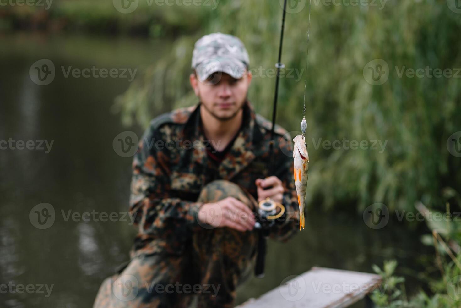 Fishing in river.A fisherman with a fishing rod on the river bank. Man fisherman catches a fish pike.Fishing, spinning reel, fish, Breg rivers. - The concept of a rural getaway. Article about fishing photo