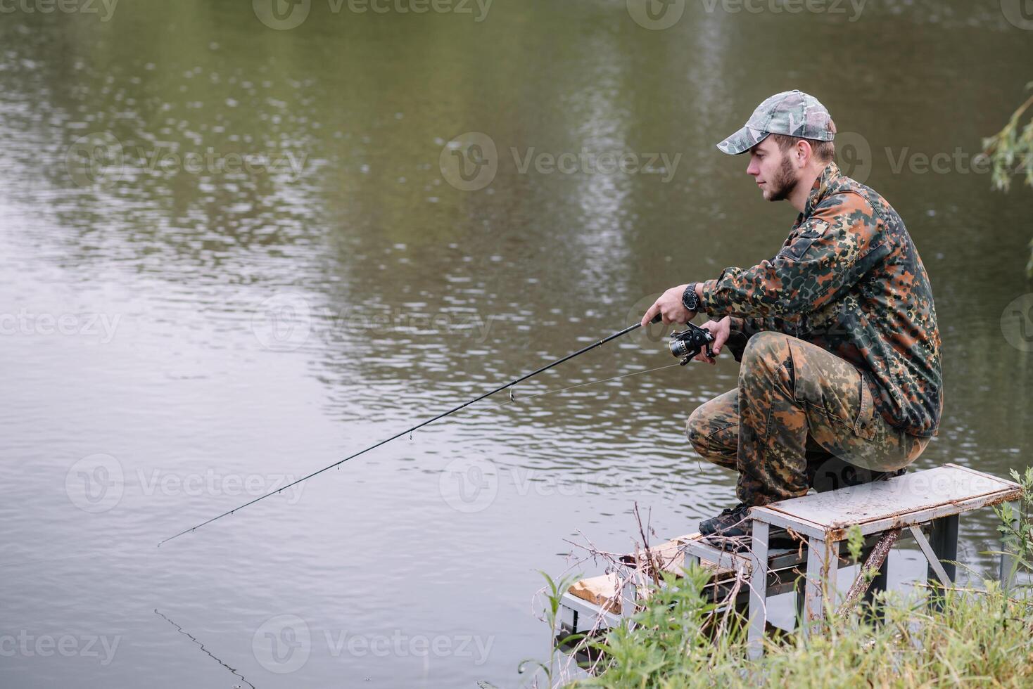 Fisherman on the summer background. Fisherman in his hand holding spinning. Fishing, spinning reel, fish, Breg rivers. - The concept of a rural getaway. Article about fishing photo