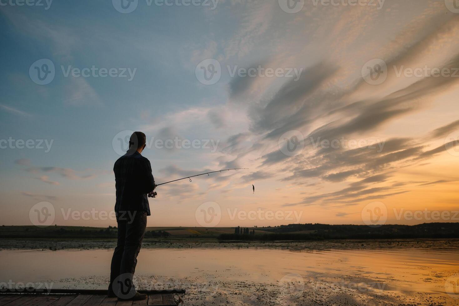 Fishing. spinning at sunset. Silhouette of a fisherman. photo