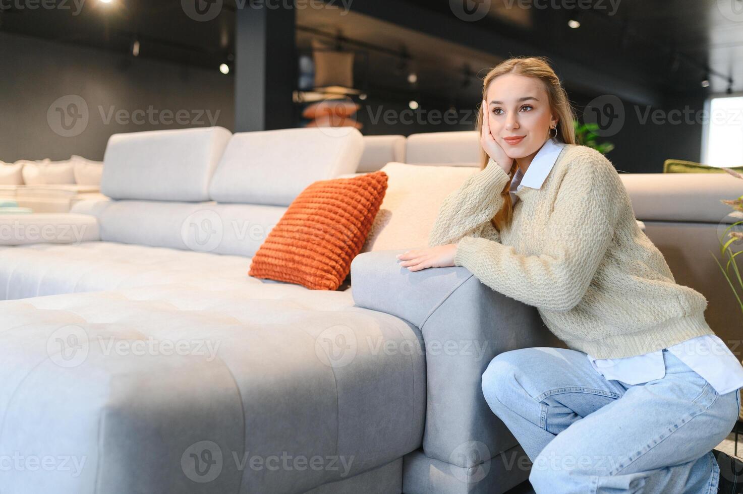 Happy young woman chooses sofa for home in furniture store photo
