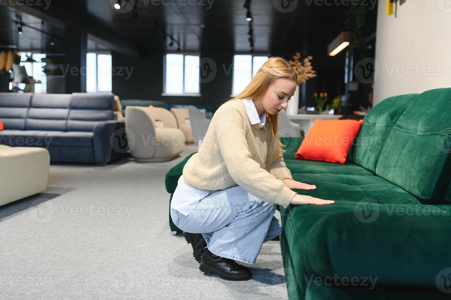 Happy young woman chooses sofa for home in furniture store photo