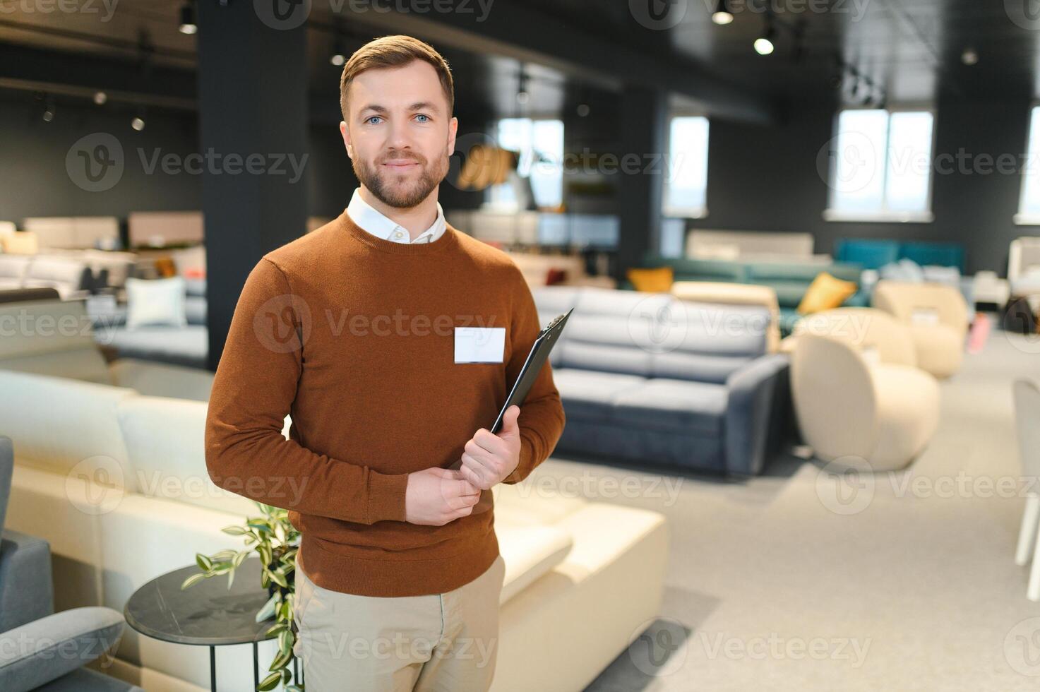 Confident salesman standing in furniture store exhibition center photo