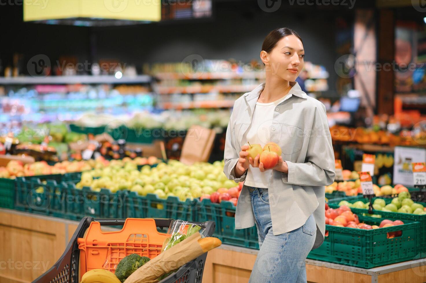 young adult woman choosing apples in grocery store. lifestyle photo