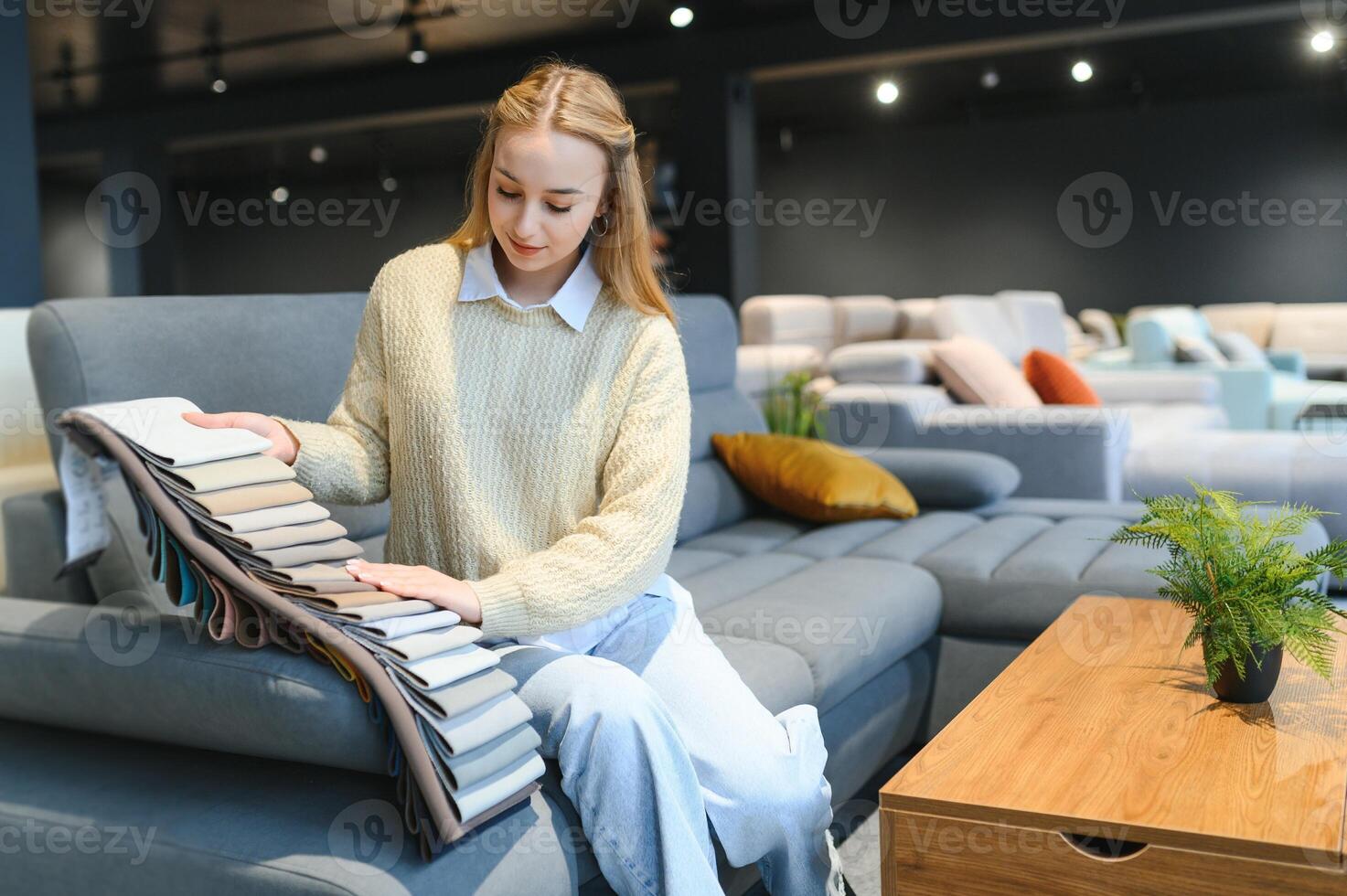 mujer diseñador a mueble Tienda mirando a textil muestra de tela foto