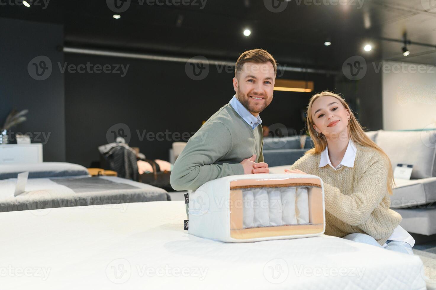 Couple buying new bed with orthopedic mattress in furniture store photo