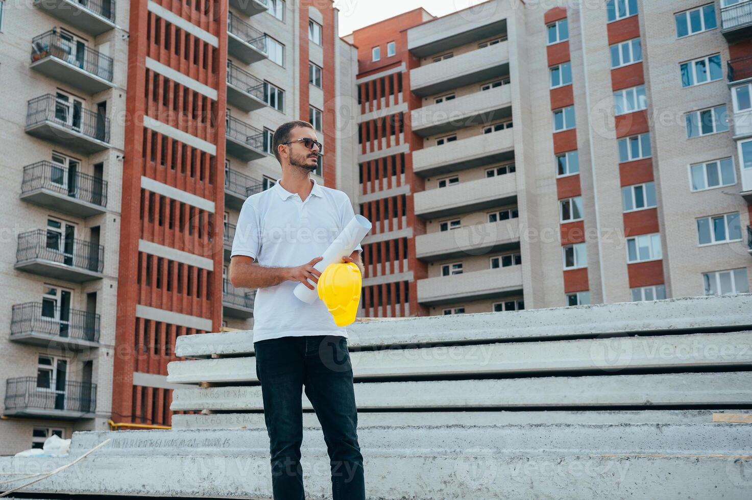 Portrait of an architect builder studying layout plan of the rooms, serious civil engineer working with documents on construction site. photo