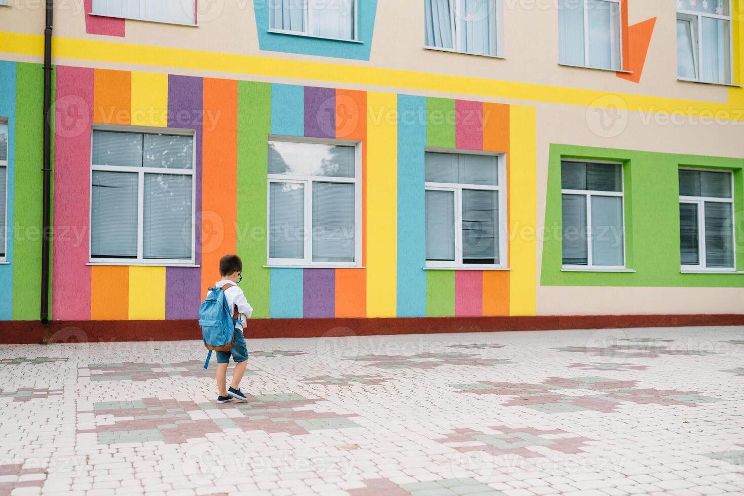 pequeño chico yendo espalda a escuela. niño con mochila y libros en primero colegio día. espalda vista. colegio concepto. espalda a escuela. foto