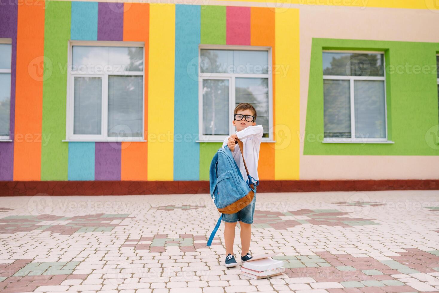 linda colegial en blanco camisas y un lentes con libros y un mochila. espalda a colegio foto