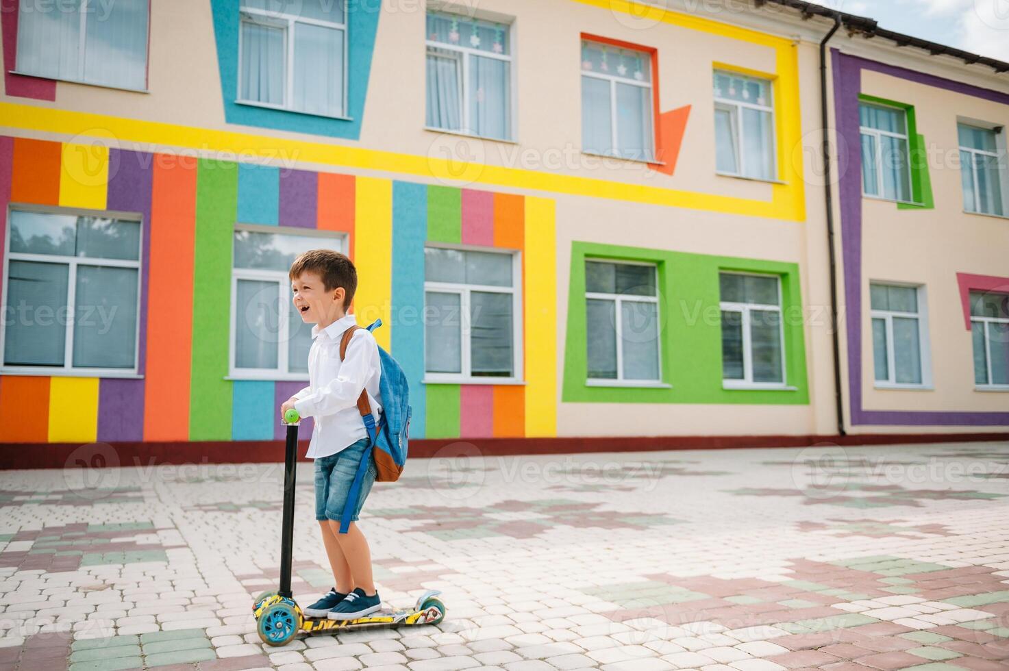 Boy goes to school on a scooter. Children back to school scoote.Childschool riding a scooter. Back to school. Happy children. Happy childhood lifestyle. Student goes to school photo