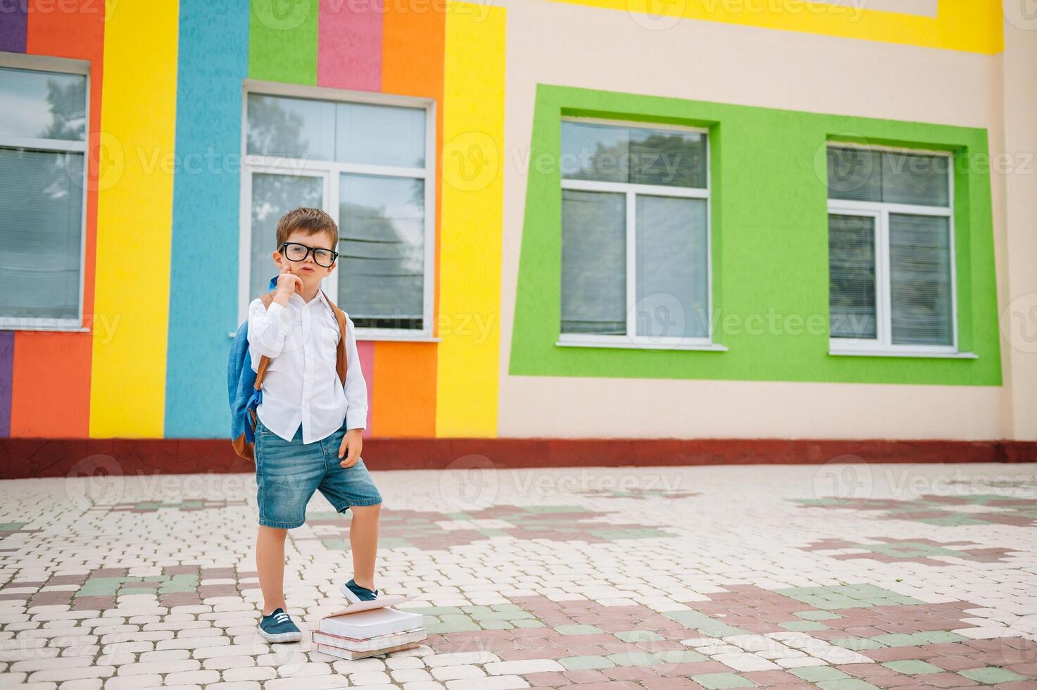 linda colegial en blanco camisas y un lentes con libros y un mochila. espalda a escuela. foto