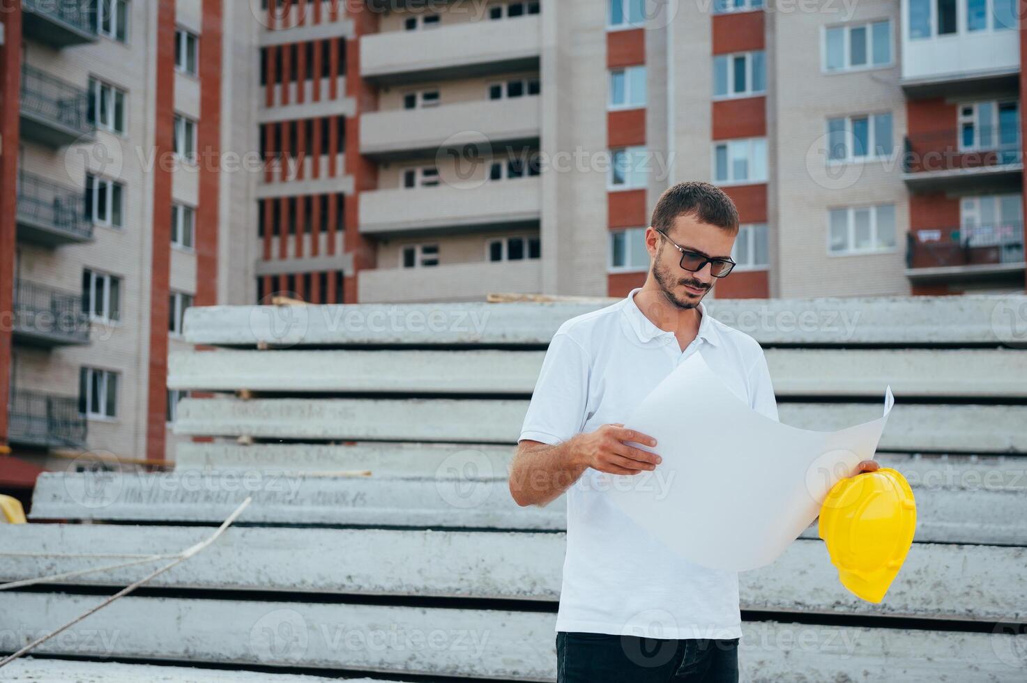 Portrait of an architect builder studying layout plan of the rooms, serious civil engineer working with documents on construction site. photo
