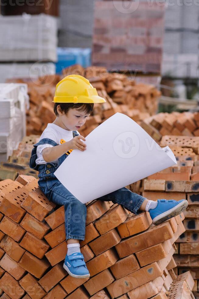 Architect in helmet writing something near new building. little cute boy on the building as an architect photo