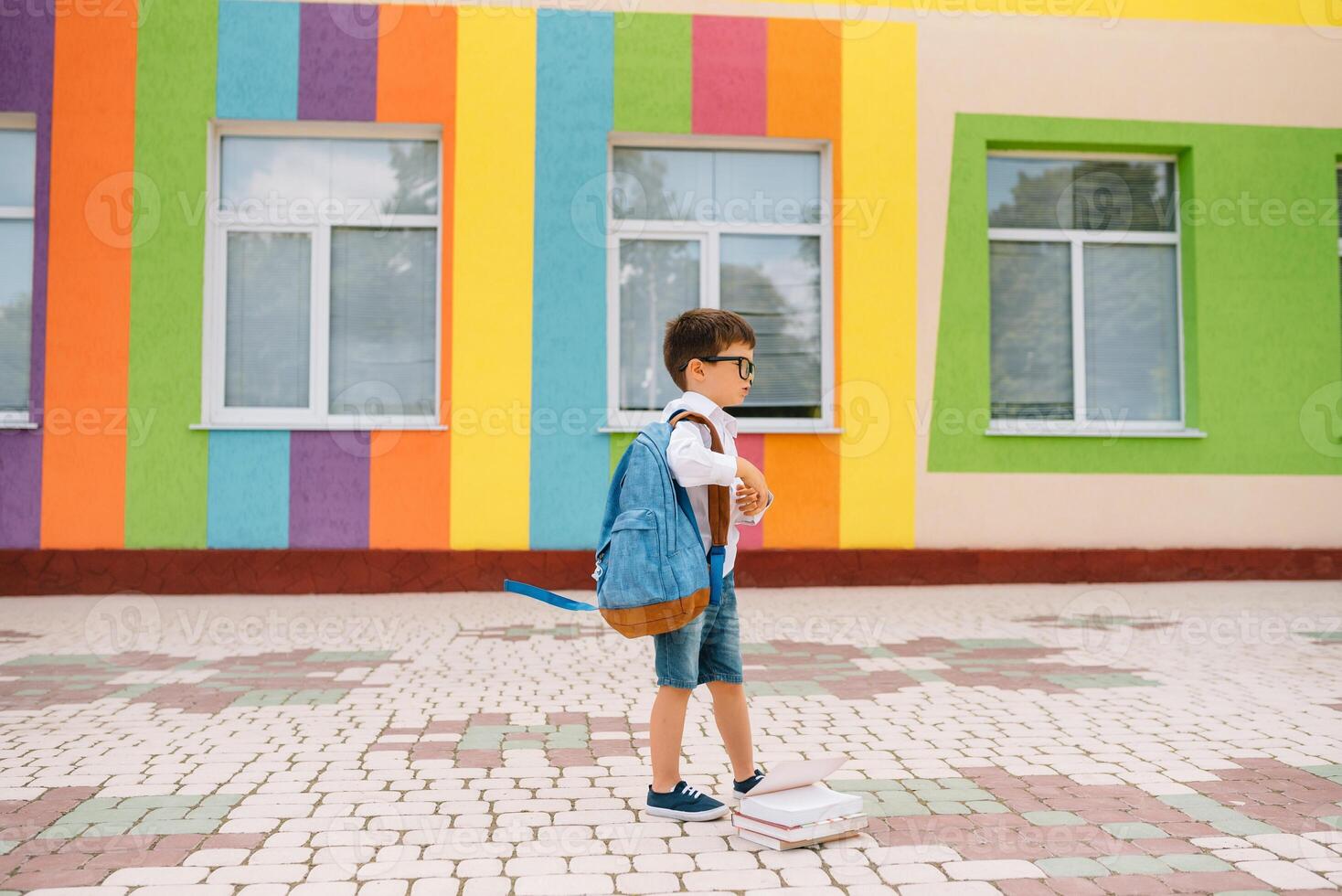 linda colegial en blanco camisas y un lentes con libros y un mochila. espalda a colegio foto