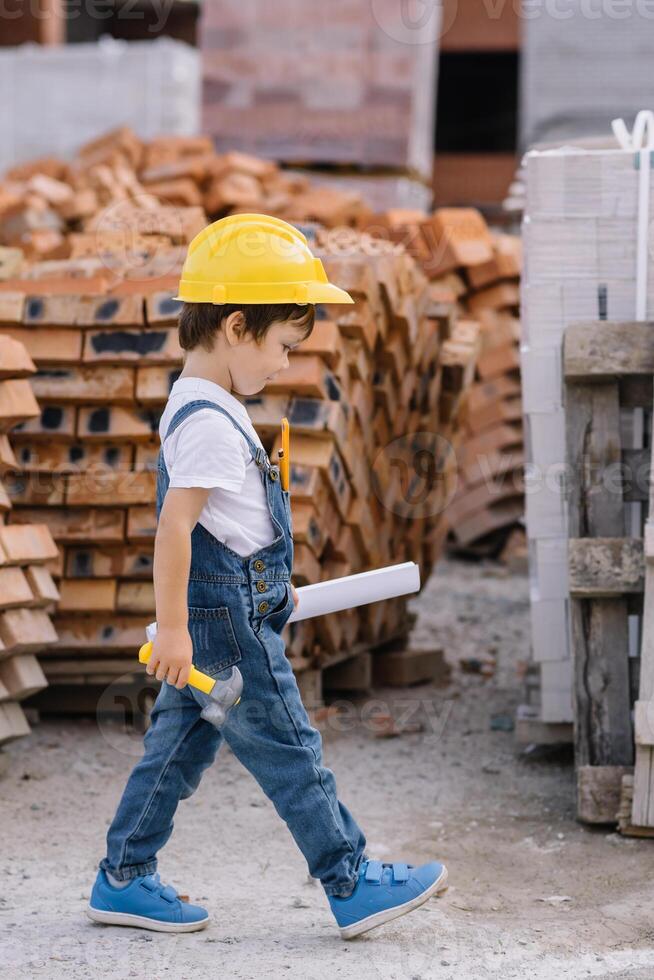 Architect in helmet writing something near new building. little cute boy on the building as an architect photo