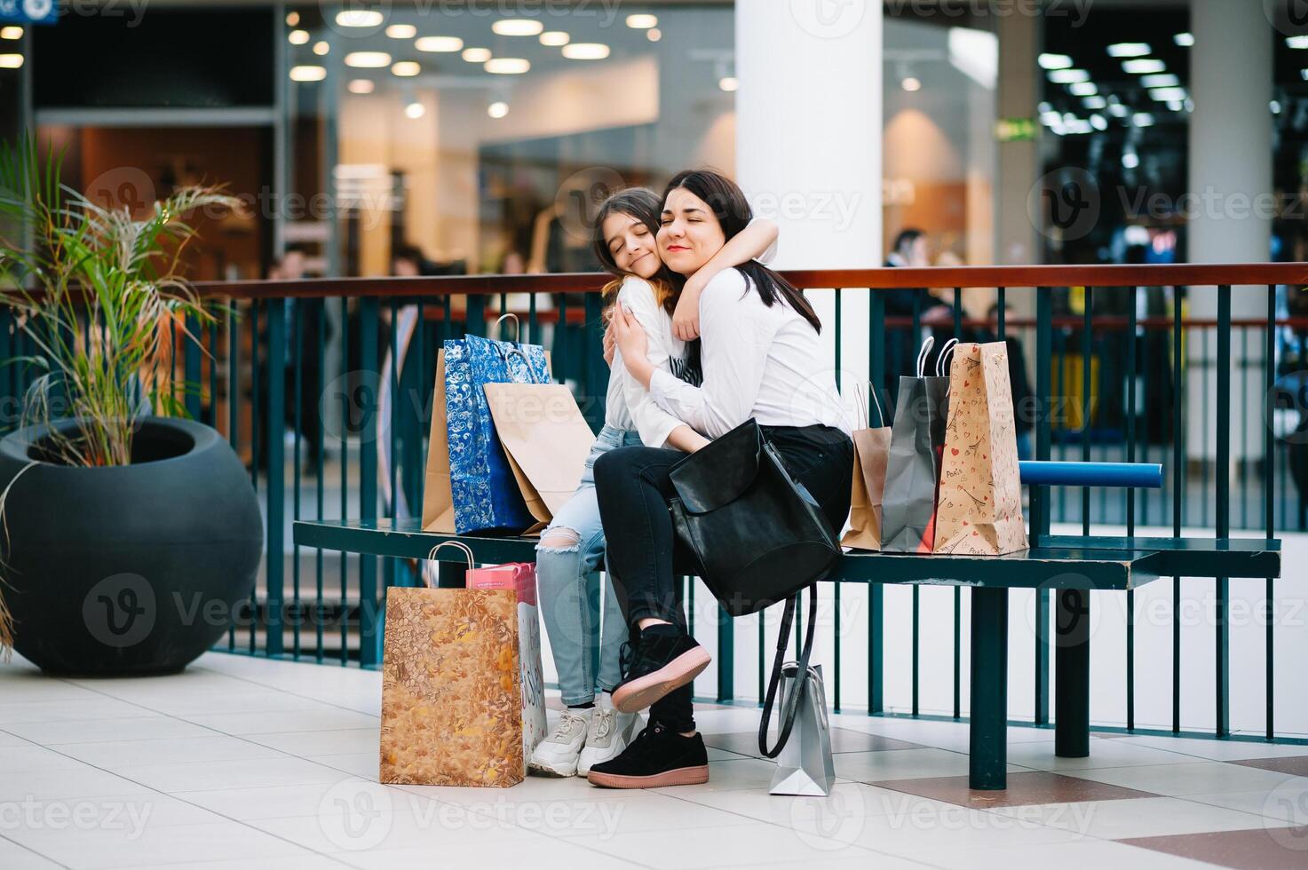 Beautiful young mom and teenage daughter are holding shopping bags, shopping in mall. Family shopping photo
