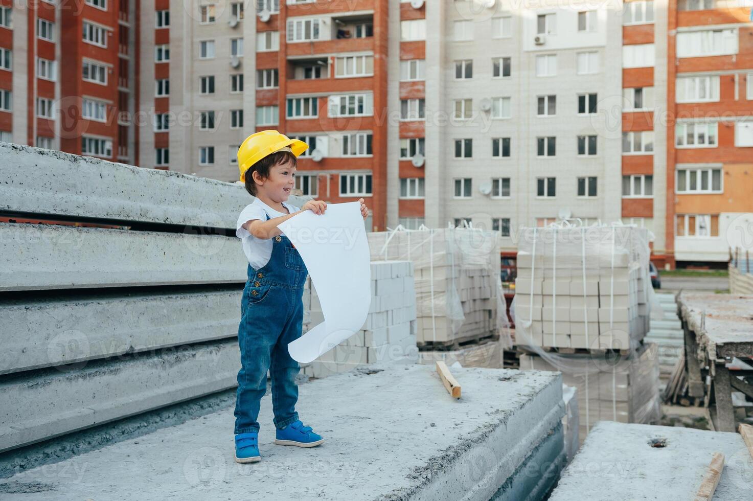 Architect in helmet writing something near new building. little cute boy on the building as an architect. photo