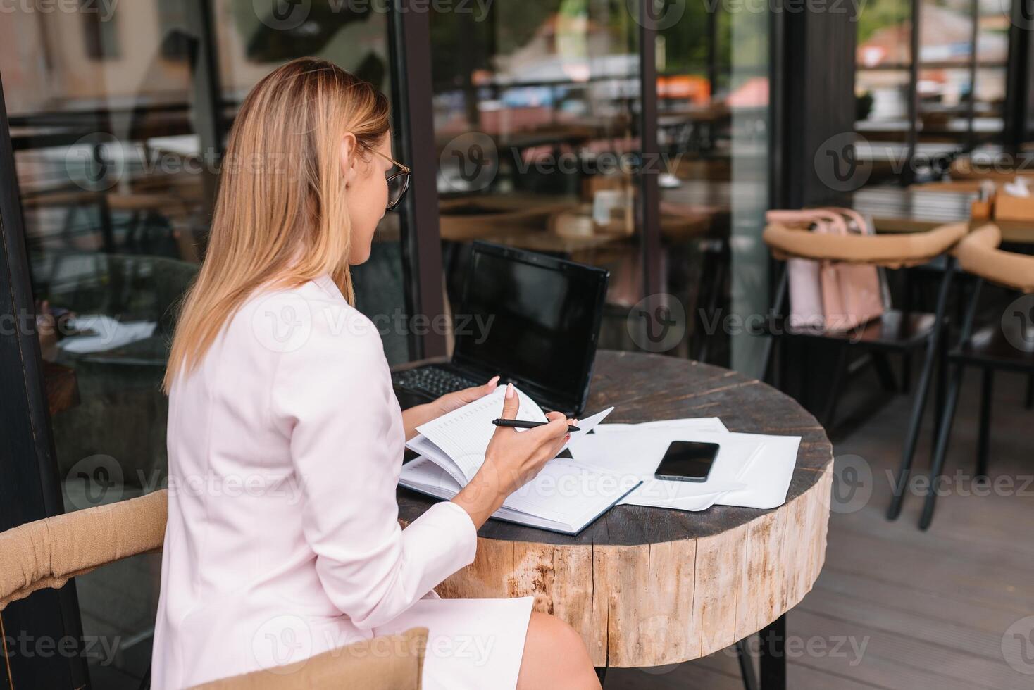 Portrait of young attractive businesswoman examining paperwork in bight light office interior sitting next to the window, business woman read some documents before meeting, filtered image. photo