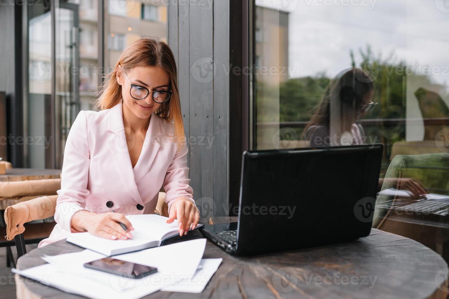 Portrait of young attractive businesswoman examining paperwork in bight light office interior sitting next to the window, business woman read some documents before meeting, filtered image. photo